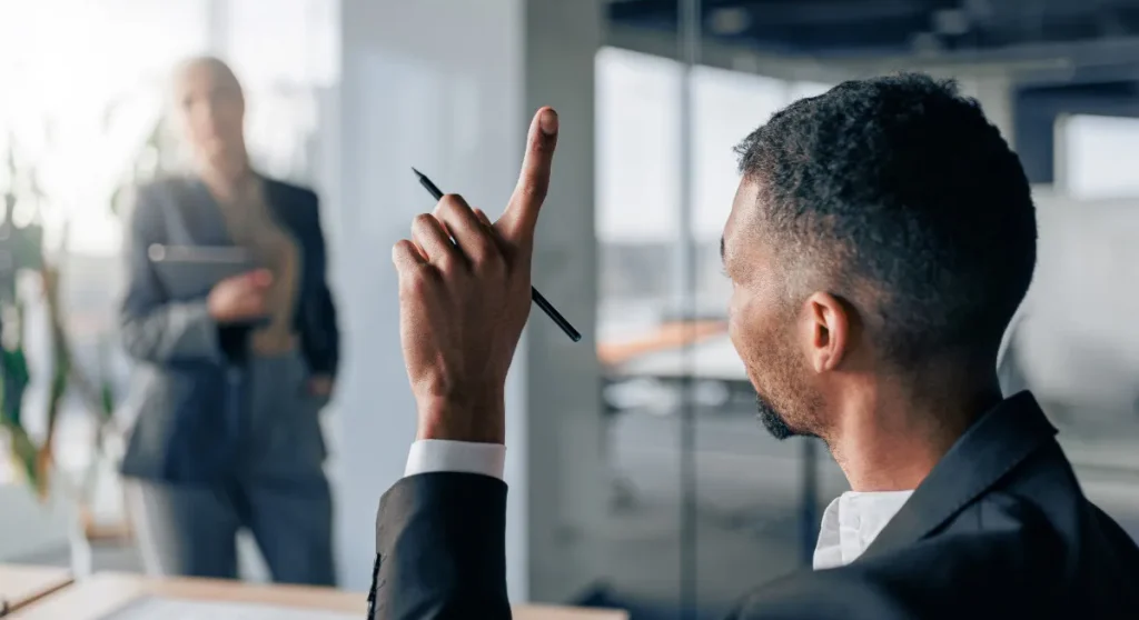 man in office raising hand holding pen to speak