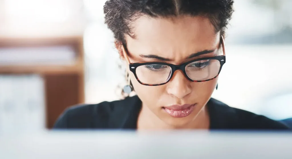 woman wearing glasses looking at computer