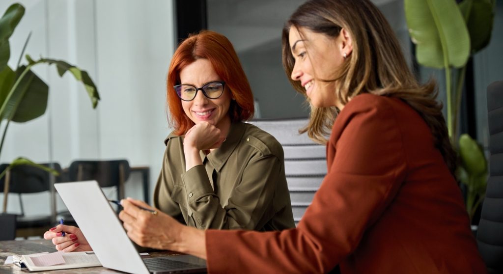 Two female colleagues using computer together