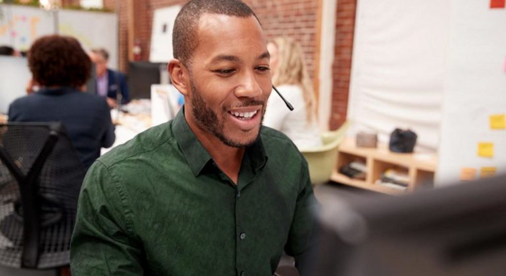 Man in a busy office environment wearing a headset