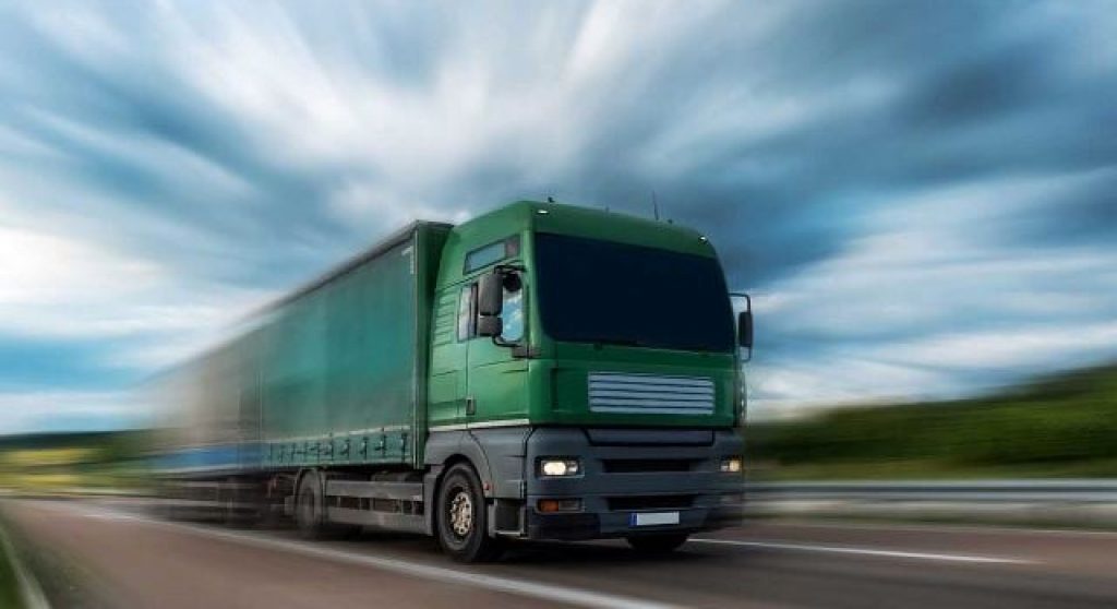 Green semi driving fast down the highway
