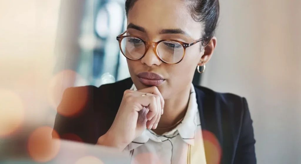 women wearing classes looking at computer thinking