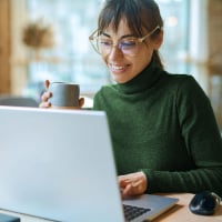 Billtrust-klant zit achter laptop met kopje koffie voor afspraak